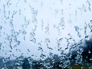 Full frame shot of wet glass against sky