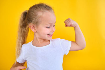 Young woman with heart shape against yellow background