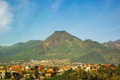 Townscape by mountain against blue sky at batu, east java, indonesia