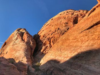 Low angle view of rocky mountain against blue sky