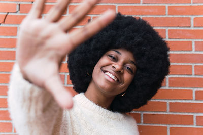 Portrait of smiling young woman standing against brick wall