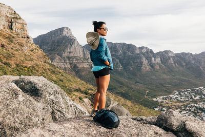 Full length of woman standing on rock against mountains