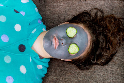 Close-up of girl with facial mask lying on bed