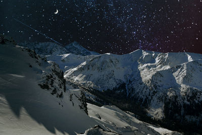 Scenic view of snowcapped mountains at night