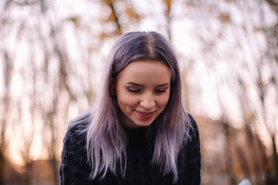 Portrait of smiling woman standing against tree