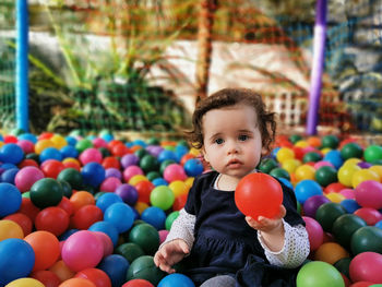 Little baby playing alone in the ball pit.