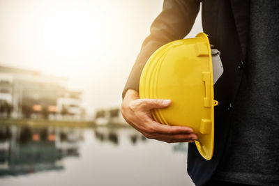 Close-up of man holding yellow while standing against built structure