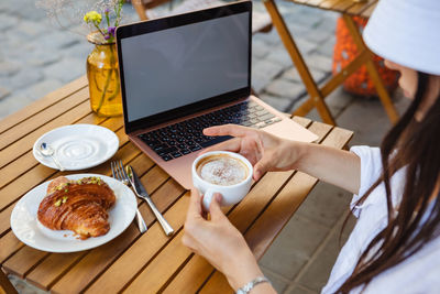 Cropped hand of woman holding coffee on table