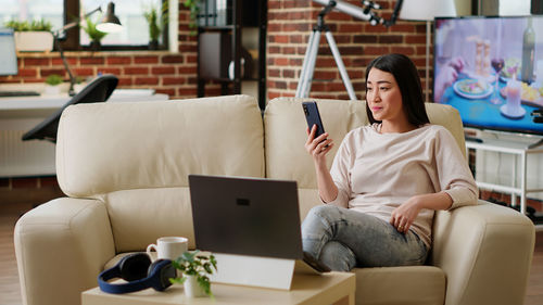 Young woman using phone while sitting at home