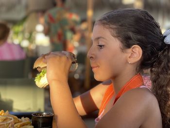 Profile view of young girl getting ready to eat a sandwich