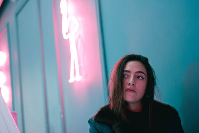 Portrait of a young woman against wall