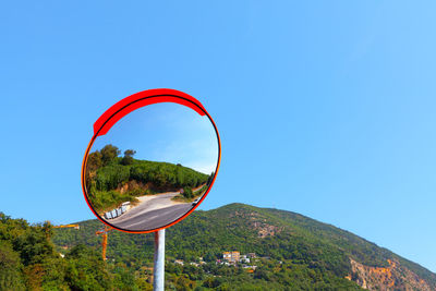 Outdoor traffic mirror with mountains on background . curved mirror. round mirror for blind spots 