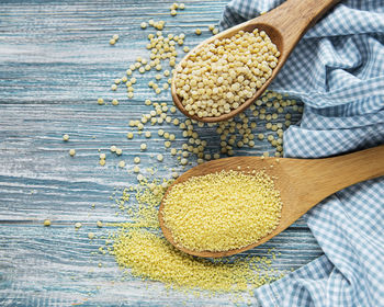 Raw couscous in a wooden spoons on the table