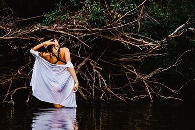 Rear view of woman standing by lake