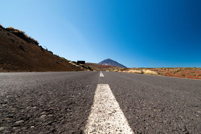 Surface level of road against clear blue sky