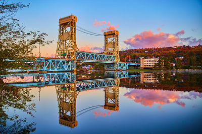 Reflection of bridge over river against sky