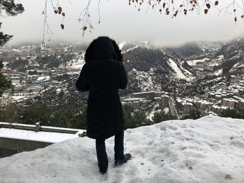 Rear view of woman standing on snowcapped mountain