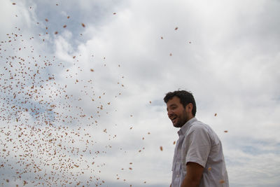 Smiling farmer standing against sky