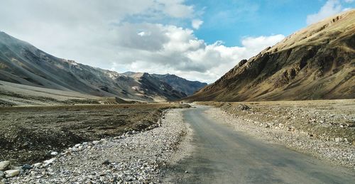 Scenic view of road by mountains against sky