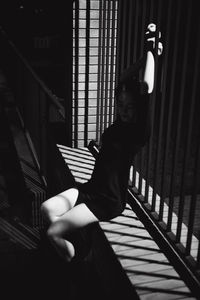 High angle view of young woman sitting on wall with fence at night