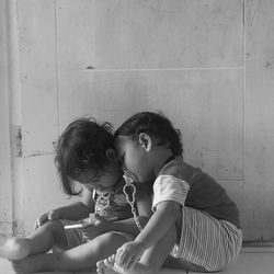 Cute kids sitting by wall at home