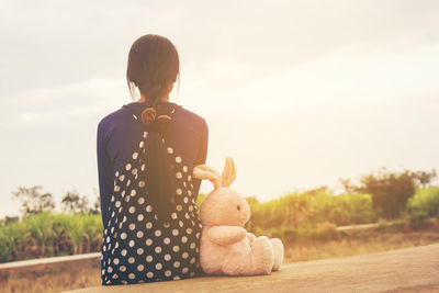 Rear view of girl with toy against sky