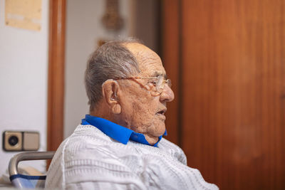 Close-up of senior man looking away while sitting at home