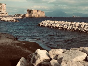 Scenic view of sea by rocks against sky