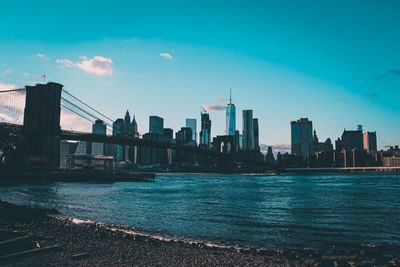 Modern buildings by river against sky in city