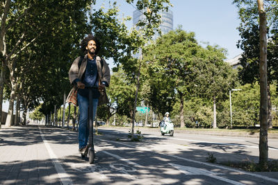 Man with backpack riding his e-scooter on a bicycle lane