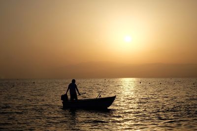 Silhouette of boat in sea at sunset