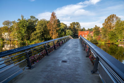 Footbridge amidst trees against sky during autumn