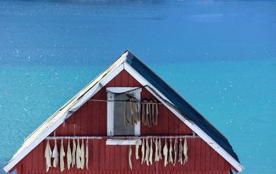 Wooden house on swimming pool by sea against blue sky