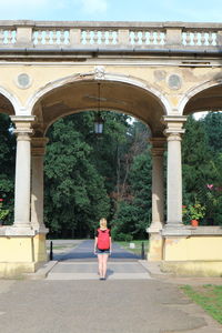 Rear view of woman standing under bridge at park