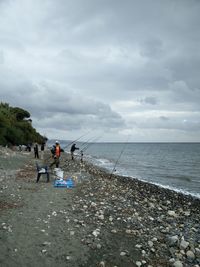 People working on beach against sky