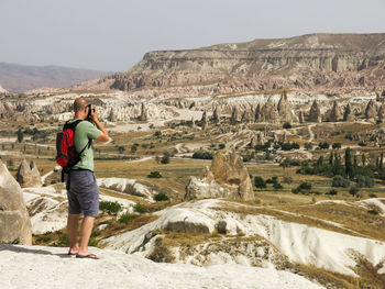 Rear view of man photographing while standing on rock formation