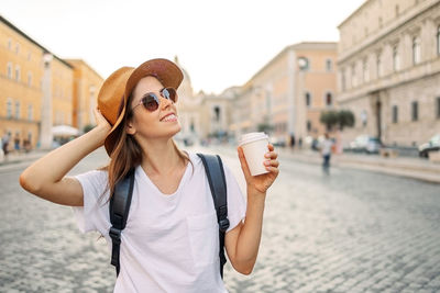 Portrait of young woman wearing sunglasses while standing in city