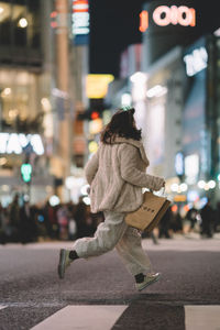 Rear view of person walking on city street at night