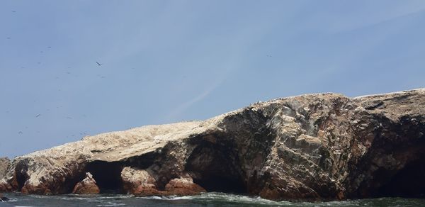 Rock formations by sea against blue sky