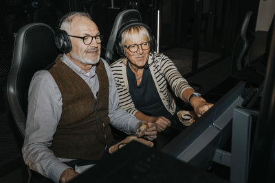 Heterosexual couple with headsets playing computer game together in gaming center during weekend