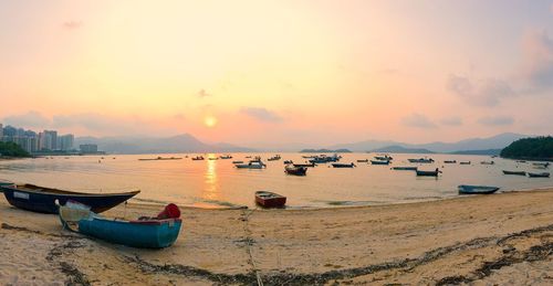 Boats moored on beach against sky during sunset