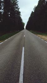 Empty road amidst trees against sky