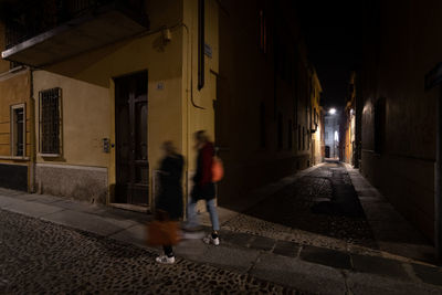 Rear view of people walking on street amidst buildings