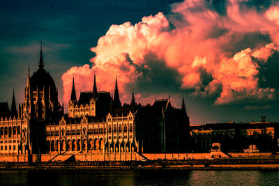 Panoramic view of buildings by river against sky during sunset