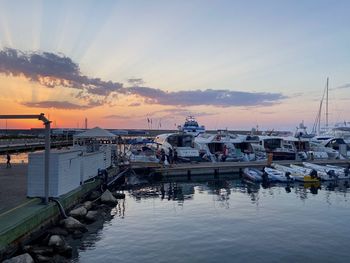 Sailboats moored at harbor during sunset