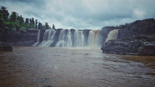 Scenic view of waterfall against sky