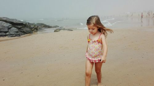 Girl standing on beach against sky