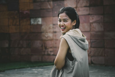 Portrait of a smiling young woman against wall