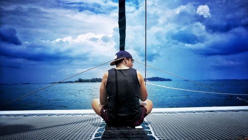 Rear view of man sitting on boat in sea