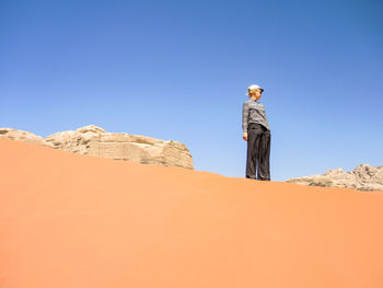 Low angle view of woman in desert against clear blue sky